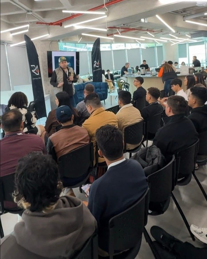 Gibrán González habla de pie ante un salón lleno, con el público sentado en filas