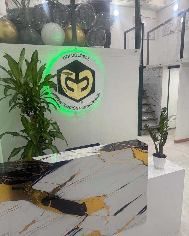 Recepción de la oficina de GoldGlobal, con el logo iluminado en verde y un mostrador de mármol