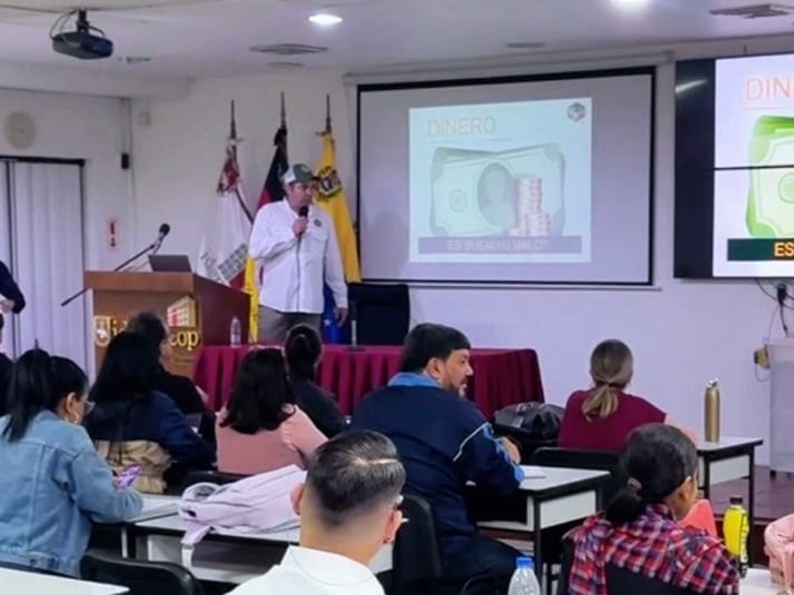 Gibrán González presenta ante un aula llena; en la pantalla, «Dinero: ¿es bueno o malo?»